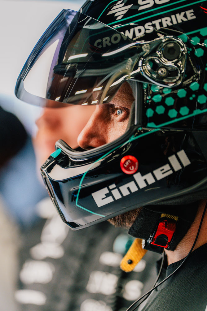 Un miembro del equipo de Fórmula 1 lleva un casco y mira al lado con concentración.