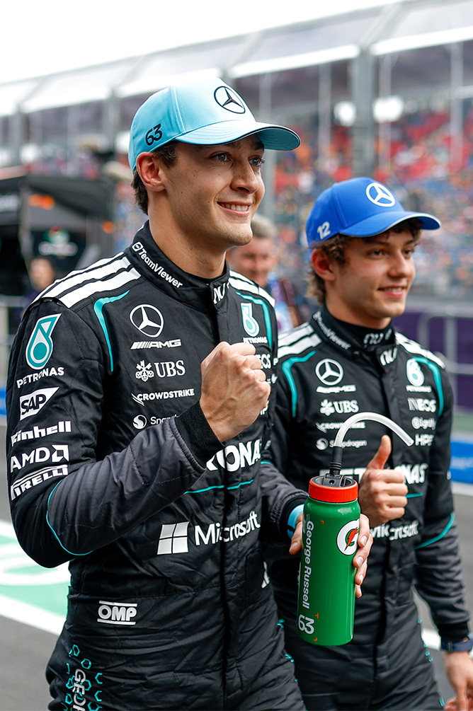 Formula 1 drivers smiling and celebrating with drinks after the race.